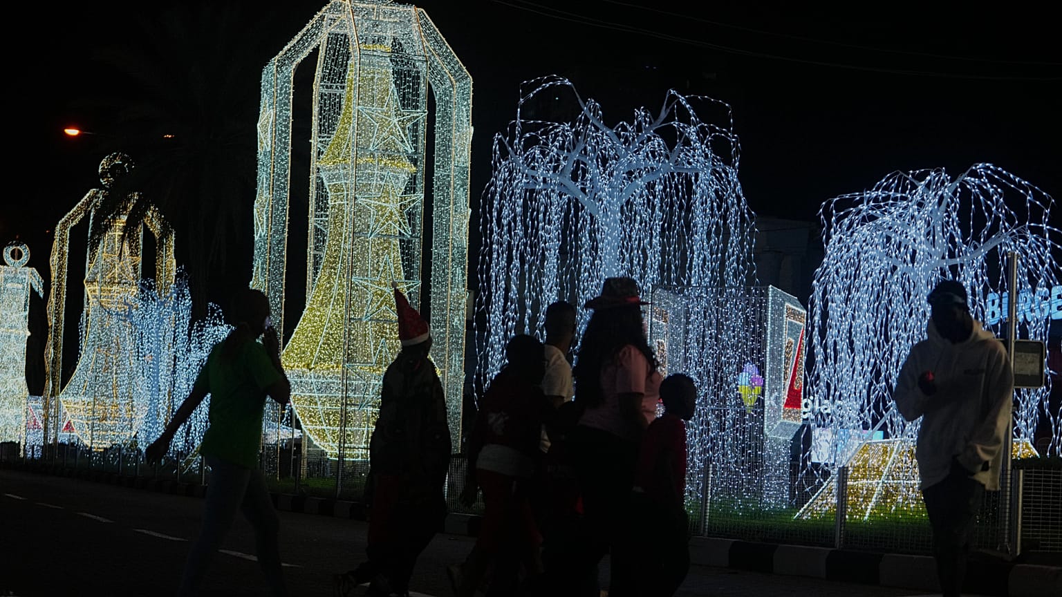 People walk past Christmas decorations on a street in Lagos, Nigeria
