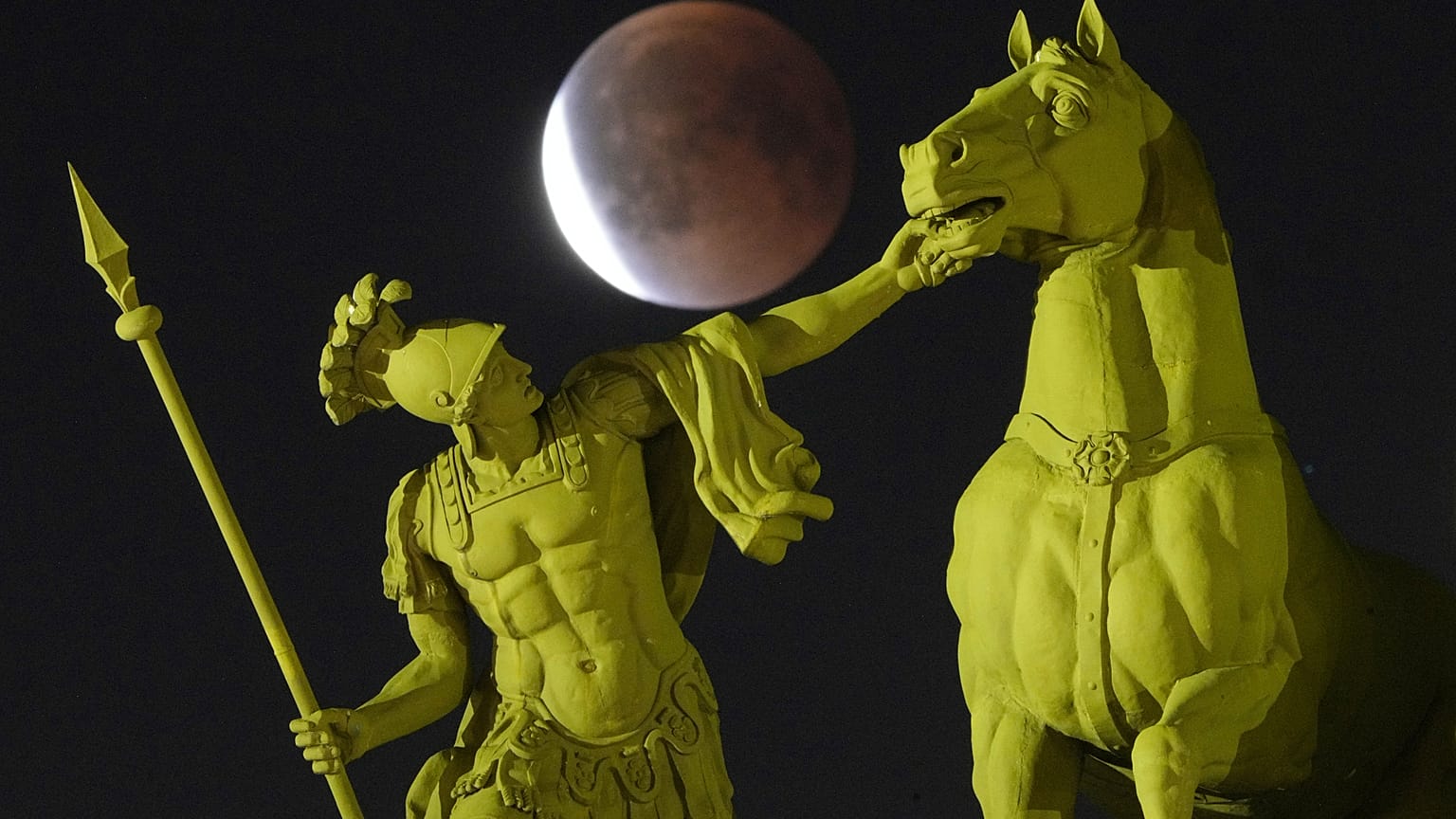 The full moon rises behind a sculpture on Palace Square in St. Petersburg during the total lunar eclipse.