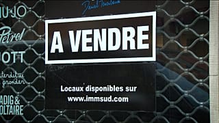 A shop displays an 'up for sale' sign after closing down