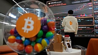 File photo - An employee watches an electronic signboard displaying the prices of Bitcoin 