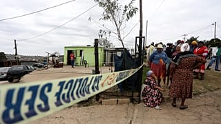 Women gather behind a police cordon where ten people from the same family were shot dead, Pietermaritzburg in the eastern KwaZulu-Natal province. Friday, April 21, 2023.