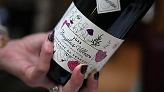 A customer pours a glass of Beaujolais Nouveau wine