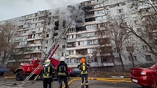 Firefighters look up at a residential building that was struck by a Russian drone, which injured several people. Tuesday, 16 December, 2025.
