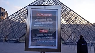 A board advises opening delays outside the pyramid of the Louvre museum in Paris, 15 December, 2025 
