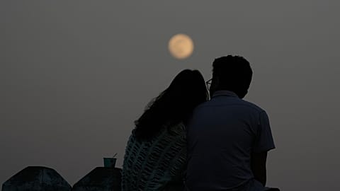A couple sits at the bank of Inya Lake while the moon rises Thursday, Dec.4, 2025, in Yangon, Myanmar.